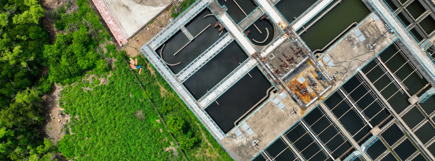 Luchtfoto van een waterzuiveringsinstallatie met vierkante en ronde waterbassins.
