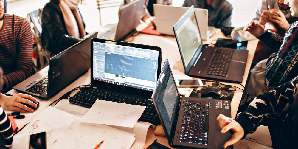 Mensen aan het werk op hun laptop in een zelfsturende organisatie.