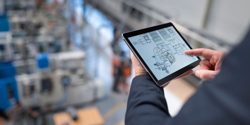 Engineer bekijkt een technische tekening op een tablet in een productiehal