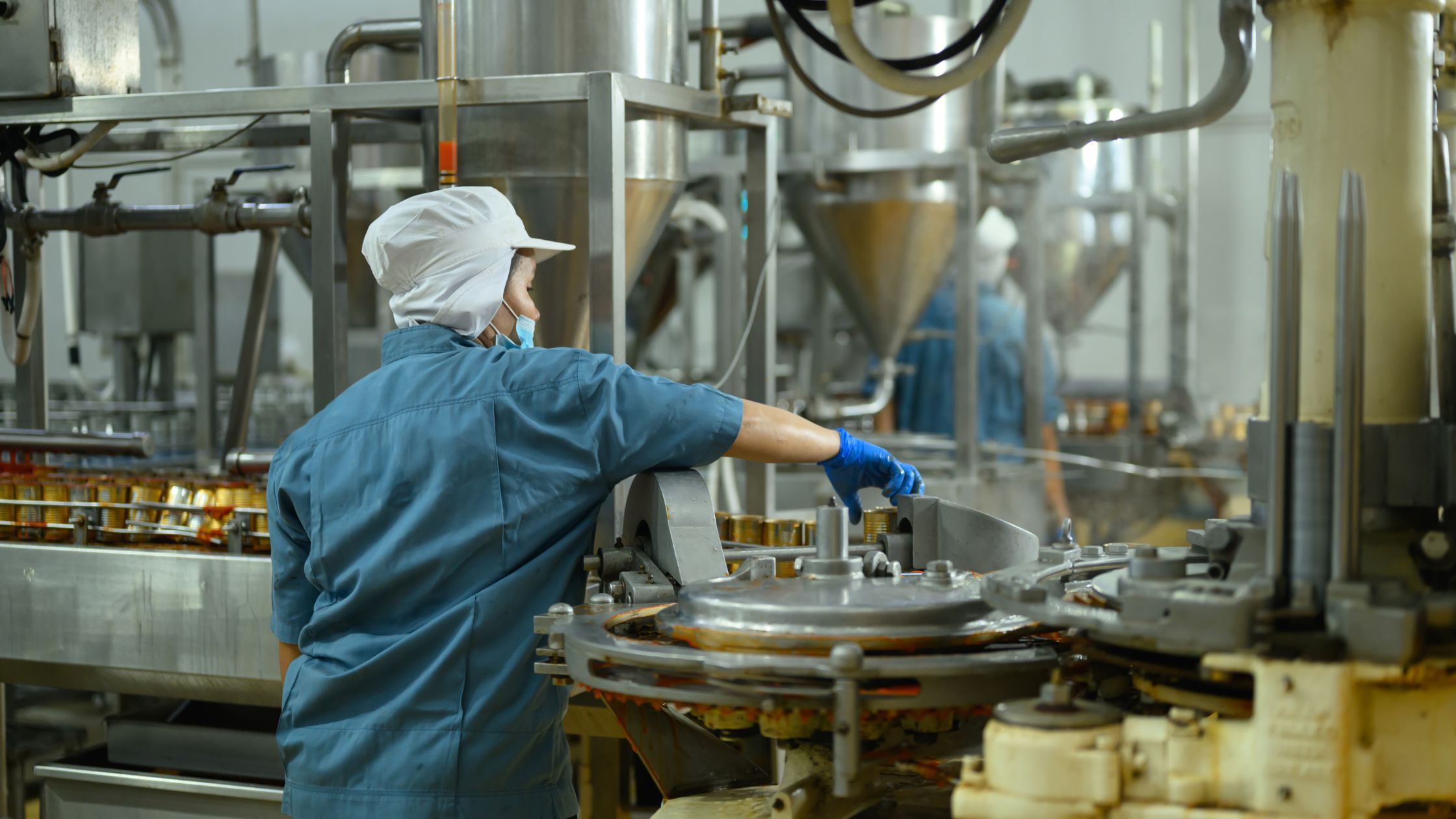 Operator in een voedselproductielijn controleert machines in een fabriek, onderdeel van procesoptimalisatie en datagedreven werken.