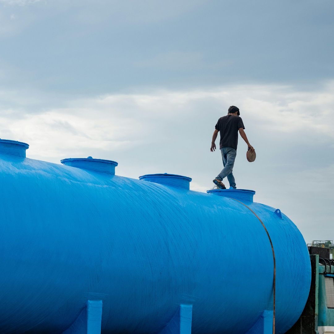 Technicus loopt over industriële opslagtank tijdens inspectie van assets op locatie