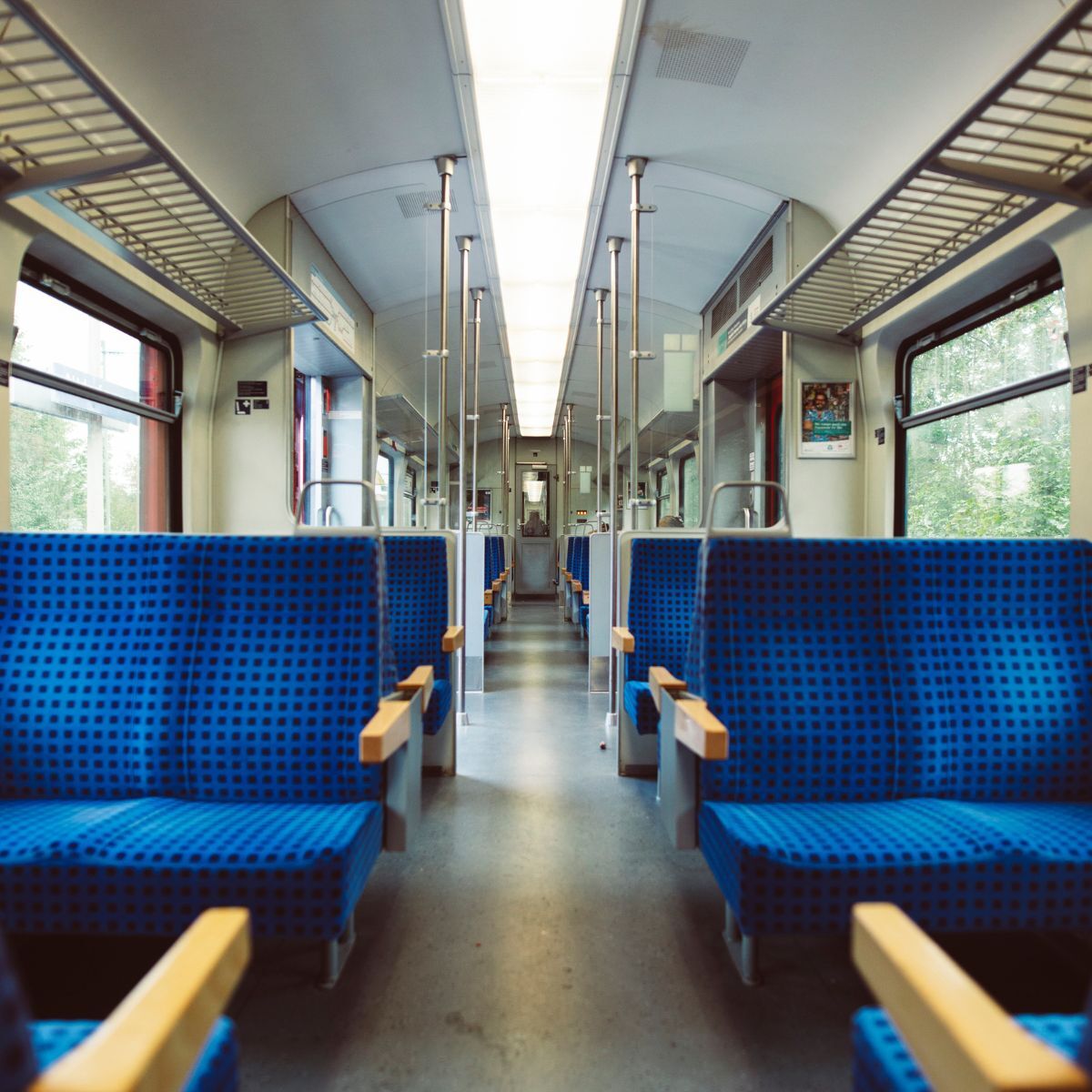 Lege treinwagon met blauwe stoelen en een doorzicht naar het einde van de coupé — symbool voor de gestroomlijnde weg naar predictive maintenance met AI.