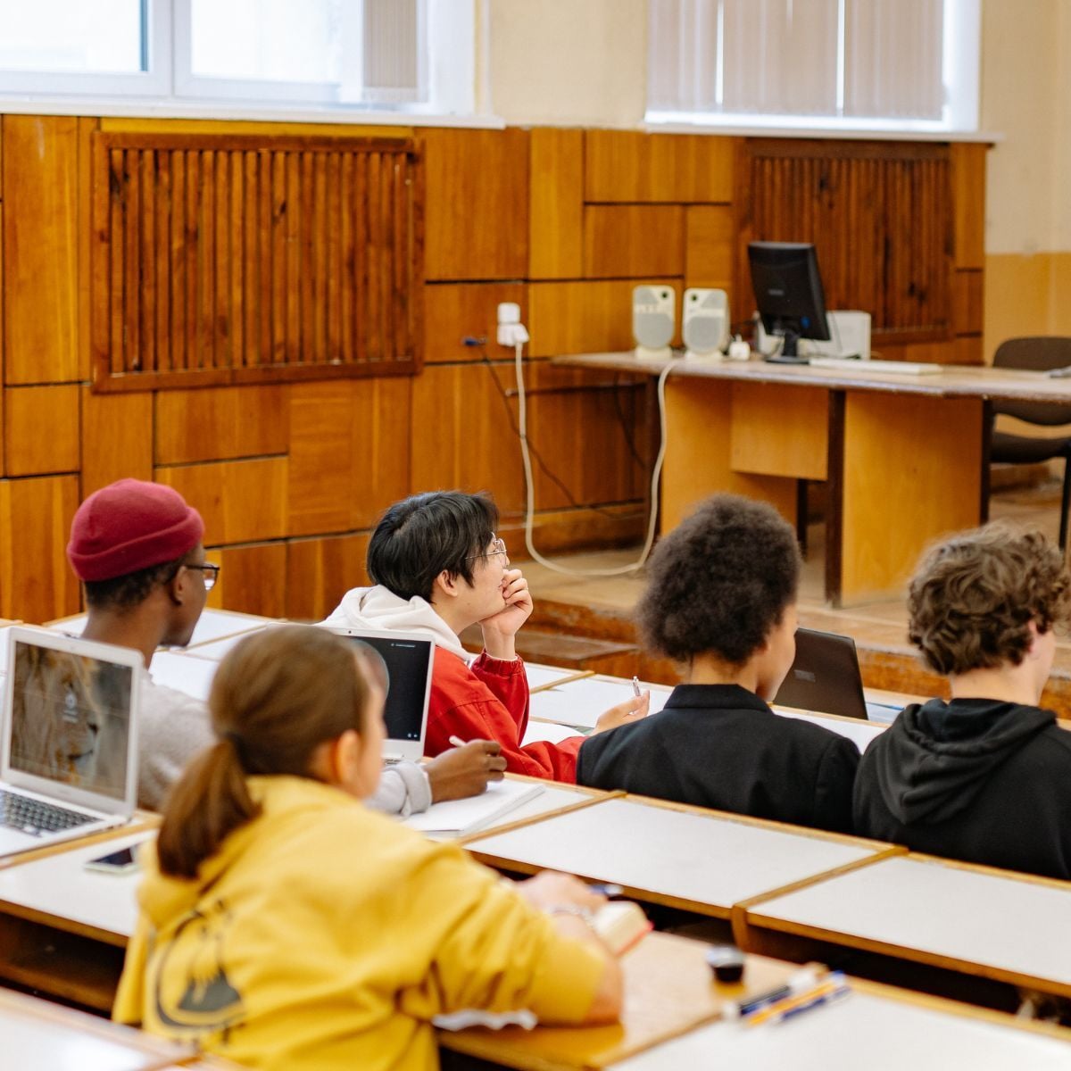 Studenten in een collegezaal die aantekeningen maken op hun laptop.